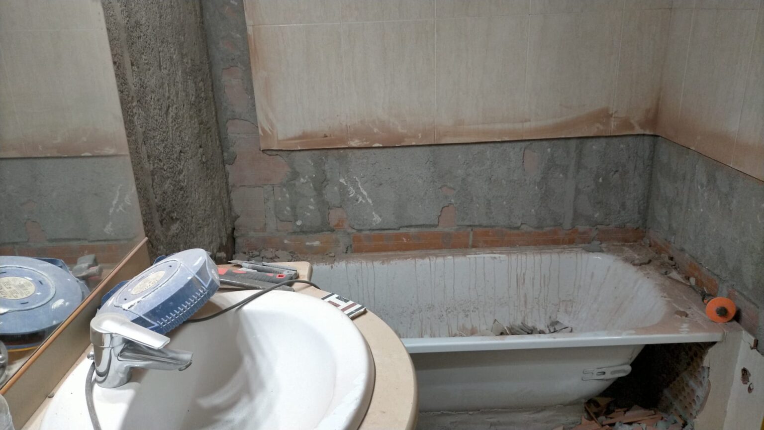 Proceso de reforma de baño en Barcelona, con paredes en obra y materiales en preparación.